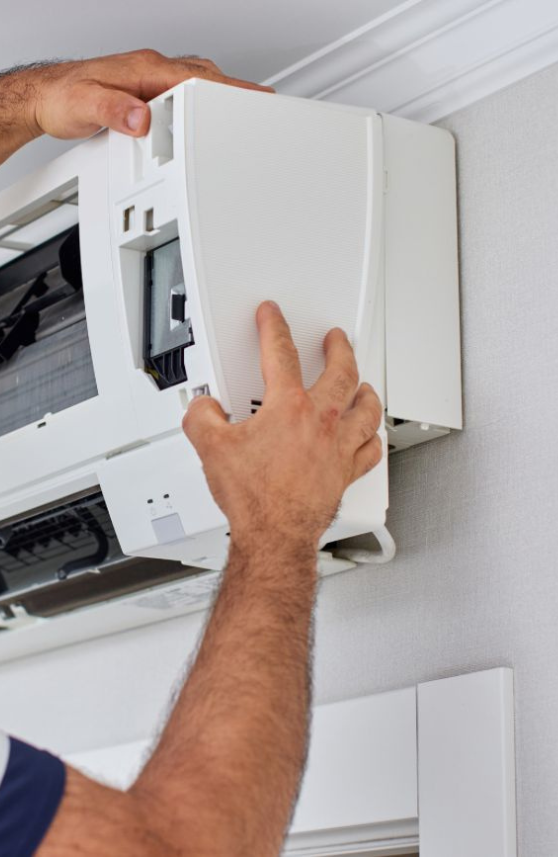 Fachmann montiert die Abdeckung einer Klimaanlage Düsseldorf an einer modernen Split-Klimaanlage.