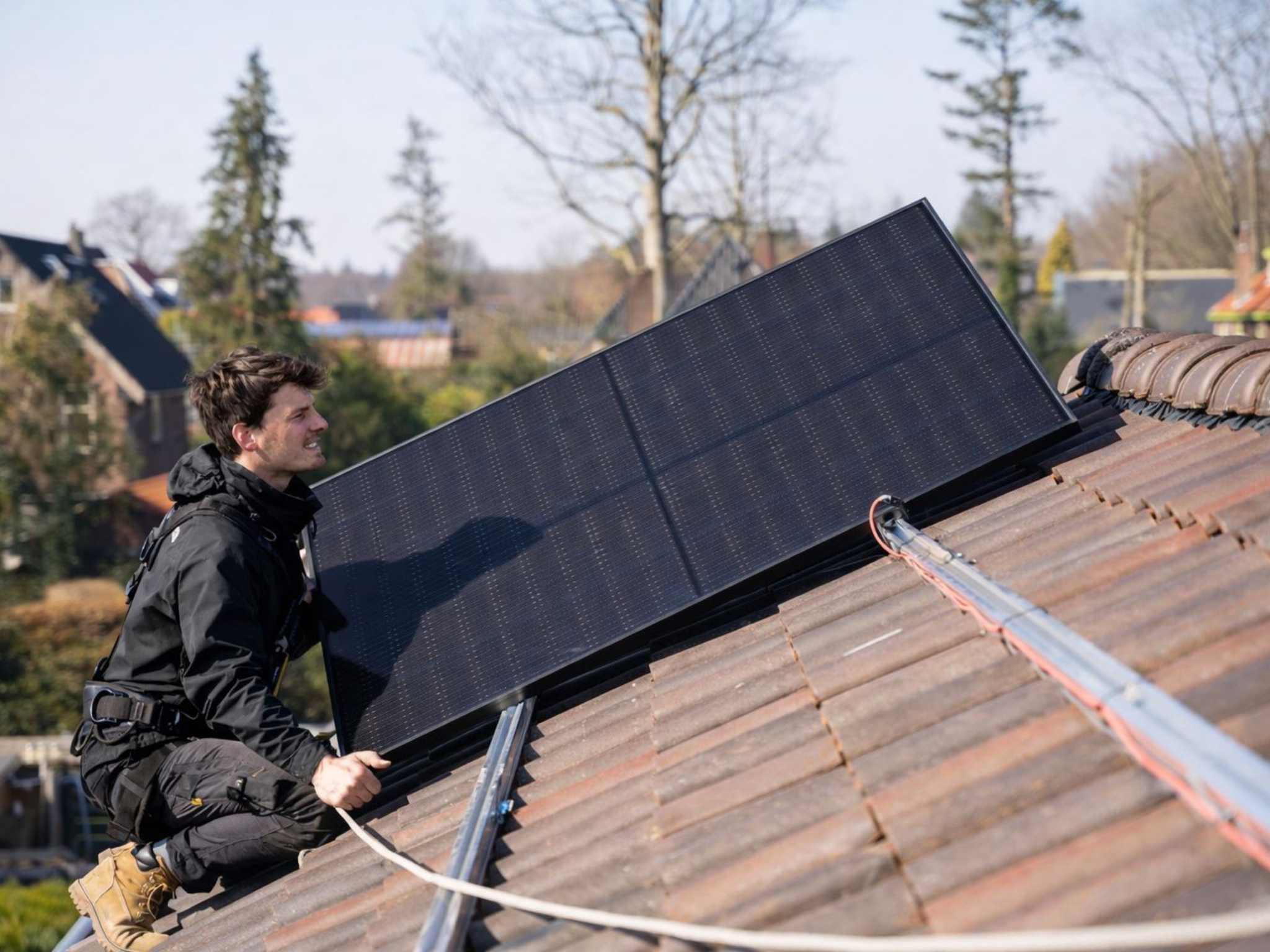 Photovoltaik Finanzierung Düsseldorf: Solaraero Installateur montiert ein Solarmodul auf einem Ziegeldach.